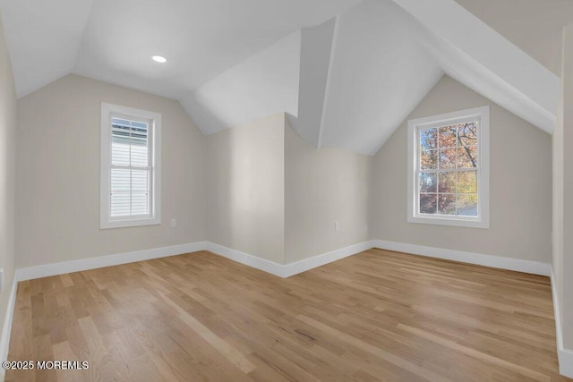 bonus room with light wood-type flooring, vaulted ceiling, and baseboards