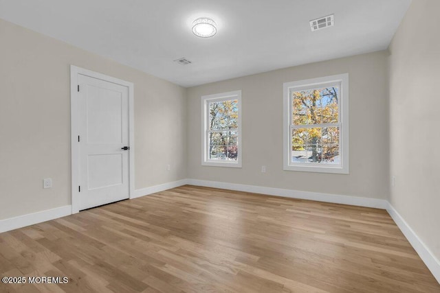 unfurnished room with light wood-type flooring, visible vents, and baseboards