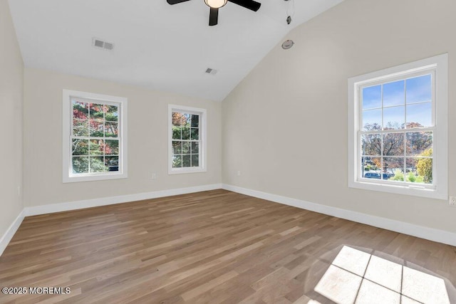 unfurnished room featuring plenty of natural light, visible vents, and vaulted ceiling