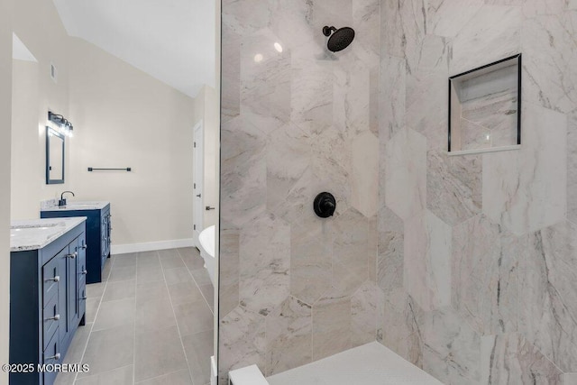 bathroom featuring two vanities, a sink, tile patterned flooring, tiled shower, and baseboards