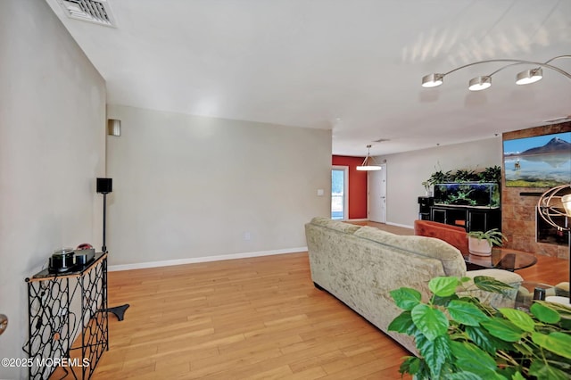 living area with light wood-type flooring, visible vents, and baseboards