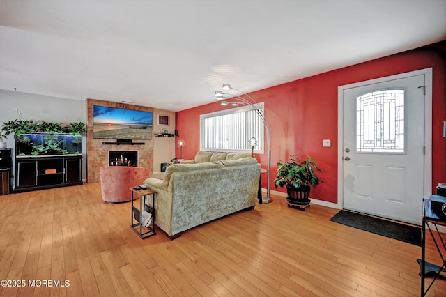 living area featuring light wood-style floors, baseboards, and a large fireplace