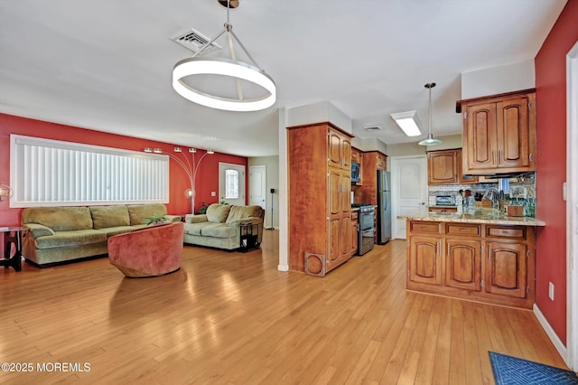 kitchen with tasteful backsplash, brown cabinetry, decorative light fixtures, stainless steel appliances, and light wood-type flooring