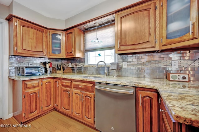 kitchen with light wood-style flooring, hanging light fixtures, backsplash, dishwasher, and brown cabinetry