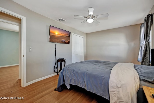 bedroom featuring light wood finished floors, a ceiling fan, visible vents, and baseboards