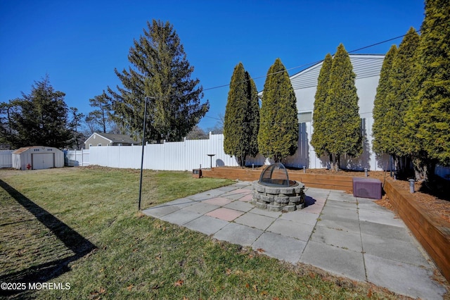 view of yard featuring an outbuilding, a fenced backyard, a fire pit, a storage unit, and a patio area