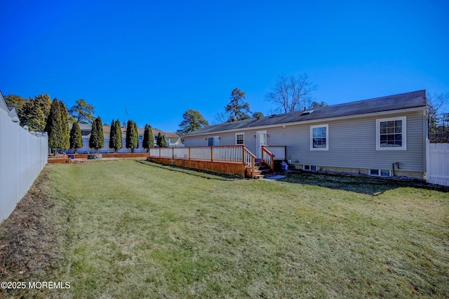 back of property with a fenced backyard, a deck, and a yard