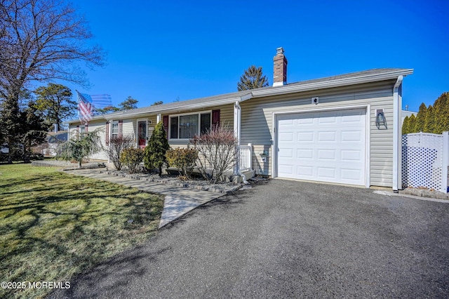 single story home with an attached garage, driveway, a chimney, and a front yard