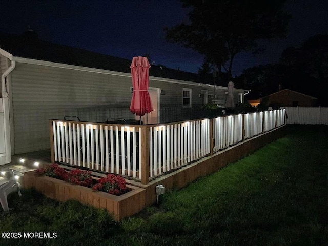 deck at night featuring fence