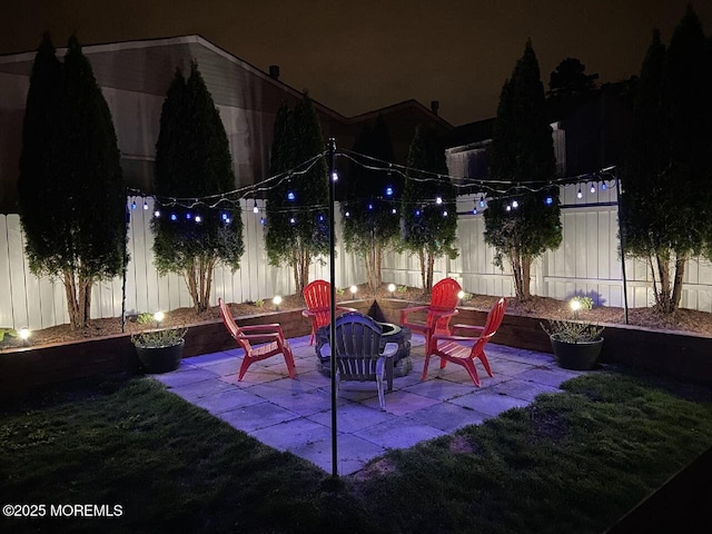 patio at twilight featuring a fire pit and a fenced backyard