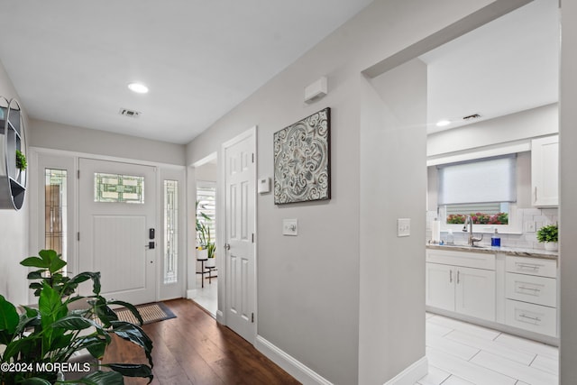 foyer with a wealth of natural light, visible vents, light wood finished floors, and baseboards