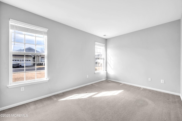 carpeted empty room with a wealth of natural light and baseboards