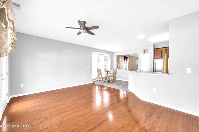 unfurnished living room with visible vents, ceiling fan, baseboards, and wood finished floors