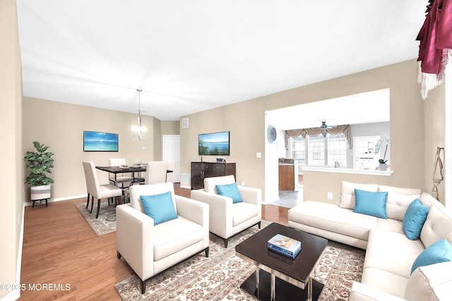 living area with light wood-style floors, baseboards, visible vents, and a chandelier