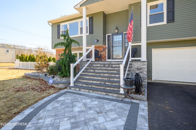 property entrance featuring a garage, brick siding, and fence