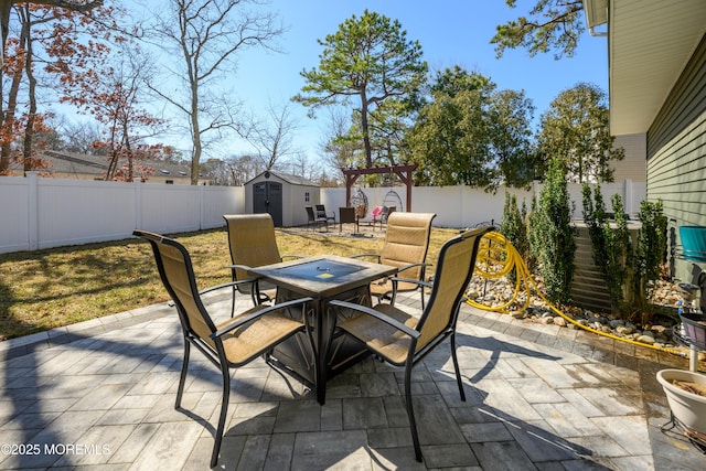 view of patio with a storage shed, outdoor dining area, an outbuilding, and a fenced backyard