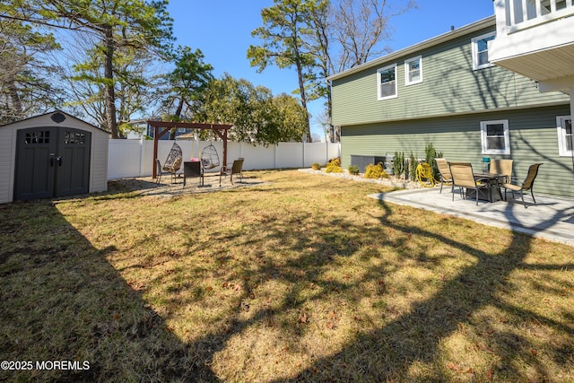 view of yard with a storage unit, a fenced backyard, an outdoor structure, and a patio area