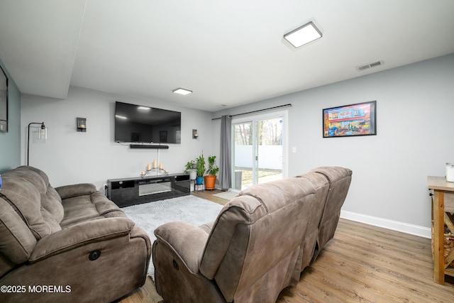 living room with visible vents, baseboards, and wood finished floors