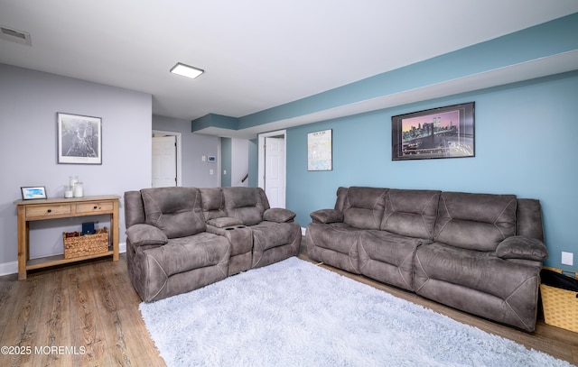 living area with visible vents, baseboards, and wood finished floors