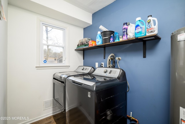 clothes washing area with wood finished floors, baseboards, laundry area, water heater, and washer and clothes dryer