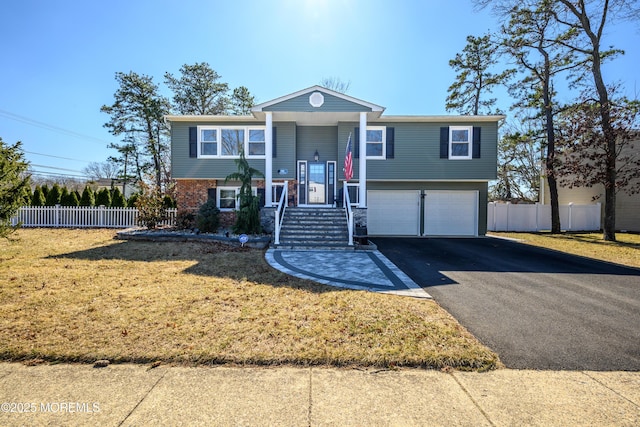 split foyer home with driveway, a front yard, a garage, and fence