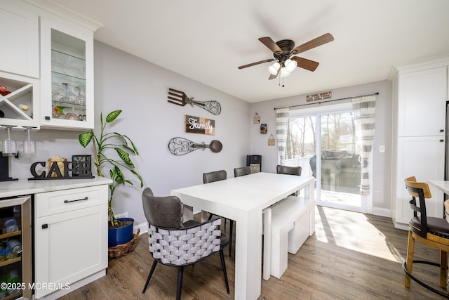 dining area with wine cooler, baseboards, dark wood-style flooring, and a dry bar