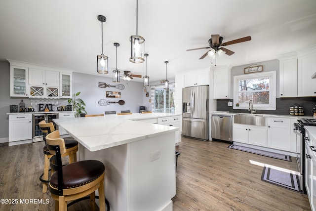 kitchen featuring beverage cooler, a breakfast bar area, decorative backsplash, stainless steel appliances, and a sink