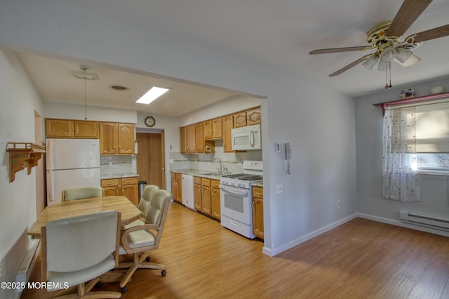 kitchen with tasteful backsplash, light countertops, light wood-style floors, a sink, and white appliances