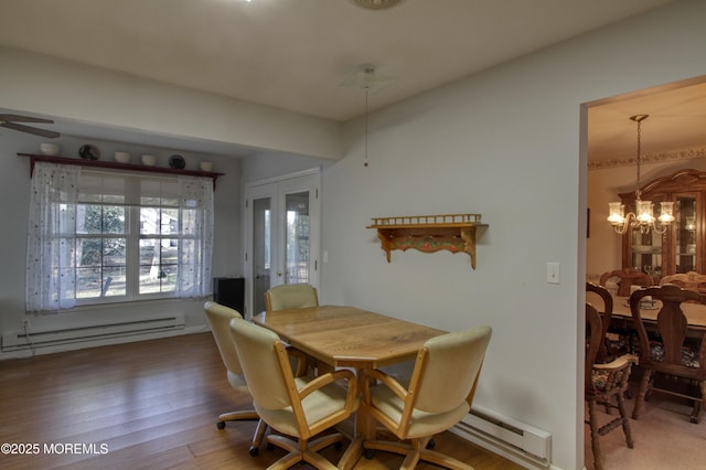 dining room with a baseboard heating unit, french doors, ceiling fan with notable chandelier, and wood finished floors