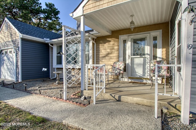 view of exterior entry featuring a porch, roof with shingles, and an attached garage