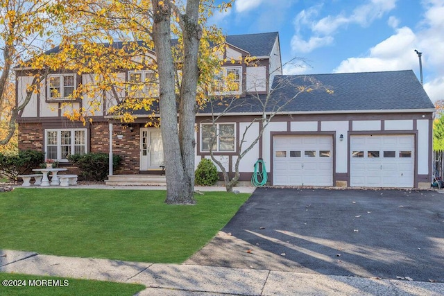 view of front of property featuring stucco siding, aphalt driveway, an attached garage, a front lawn, and brick siding