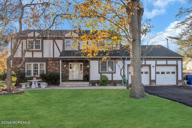 view of front of home featuring stucco siding, a garage, a front yard, and aphalt driveway