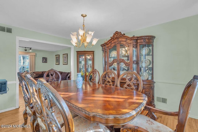 dining space featuring light wood-type flooring, visible vents, baseboards, and an inviting chandelier