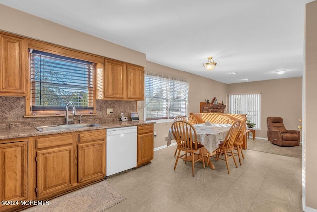 kitchen featuring light floors, white dishwasher, backsplash, and a sink