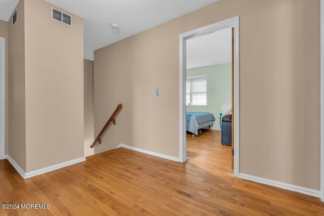 hallway with visible vents, an upstairs landing, baseboards, and light wood-style flooring