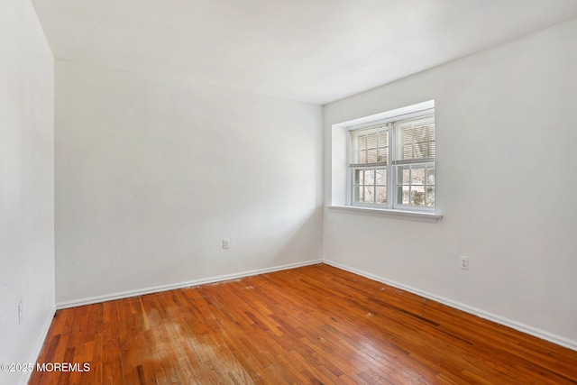 unfurnished room with baseboards and hardwood / wood-style flooring