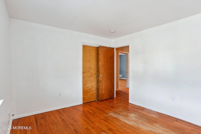 unfurnished room with baseboards and hardwood / wood-style flooring