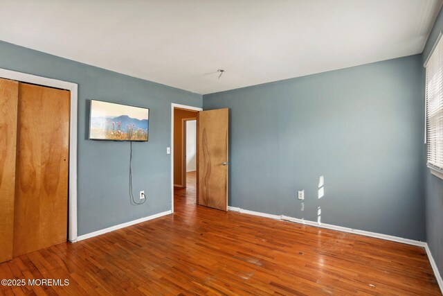 unfurnished bedroom featuring a closet, baseboards, and hardwood / wood-style floors