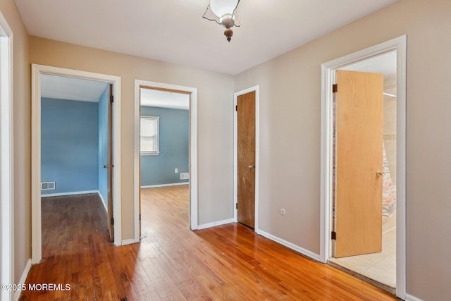 unfurnished bedroom with hardwood / wood-style flooring, baseboards, and visible vents