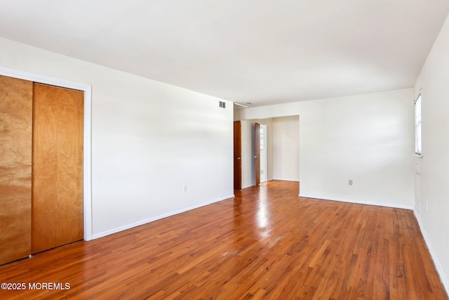 empty room with visible vents, baseboards, and wood finished floors