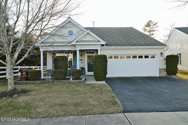 view of front facade featuring driveway, a shingled roof, stone siding, an attached garage, and covered porch