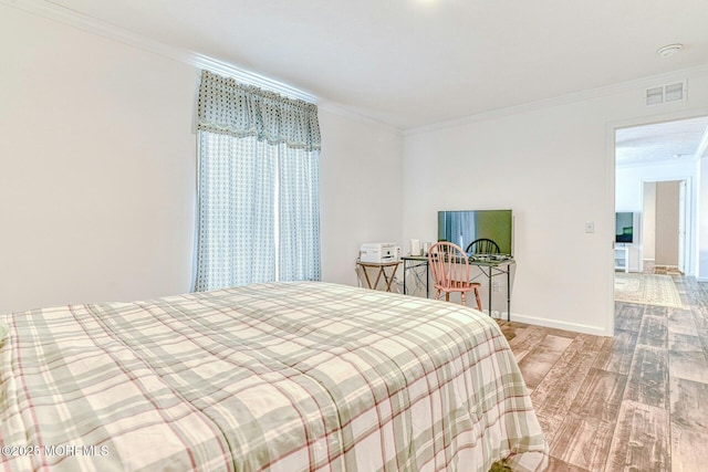 bedroom featuring ornamental molding, visible vents, baseboards, and wood finished floors