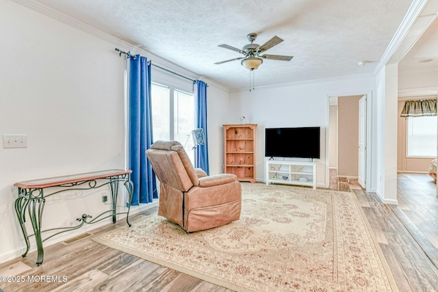 living area featuring plenty of natural light, crown molding, and wood finished floors