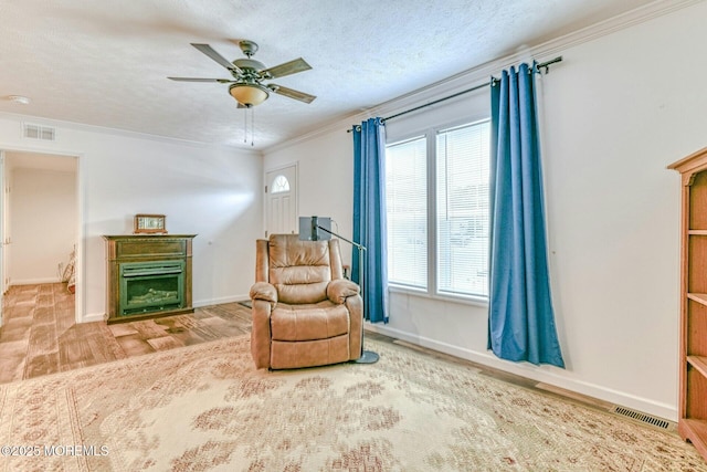 living area featuring a textured ceiling, ornamental molding, a fireplace, and visible vents