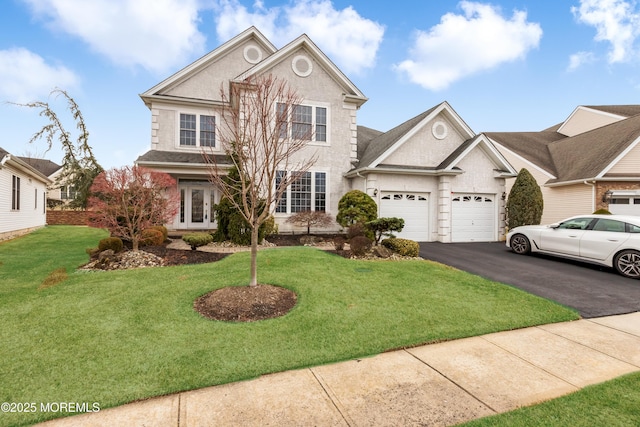 traditional home featuring french doors, aphalt driveway, an attached garage, and a front yard