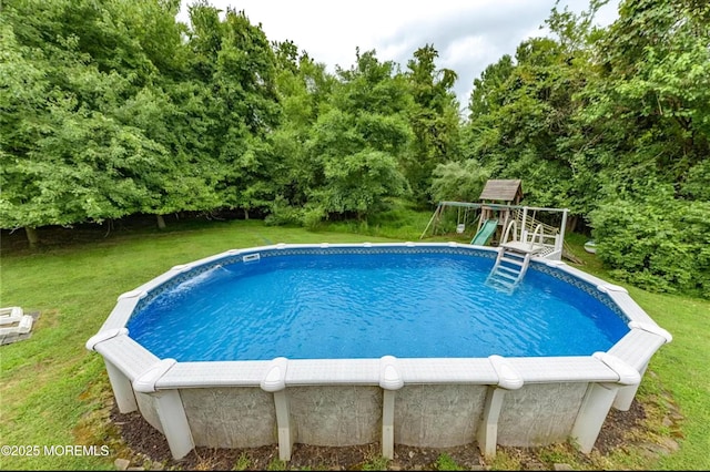 outdoor pool featuring a playground and a yard