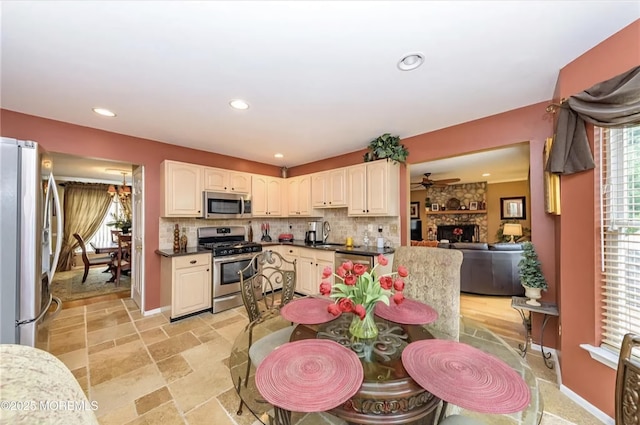 kitchen with recessed lighting, stone tile flooring, a stone fireplace, appliances with stainless steel finishes, and backsplash