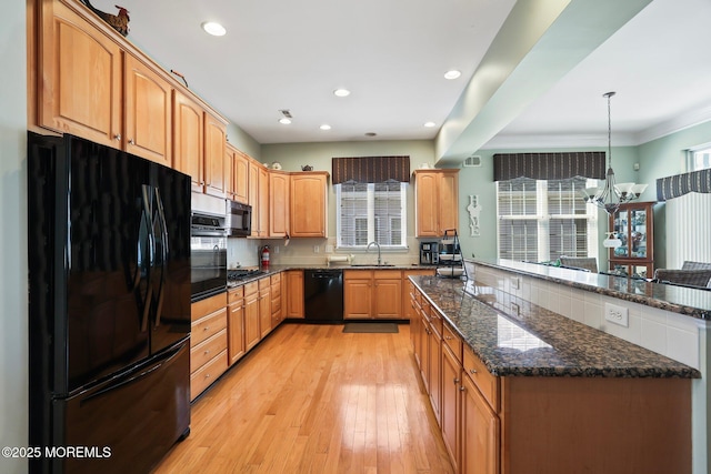 kitchen with dark stone counters, a healthy amount of sunlight, light wood-style flooring, and black appliances