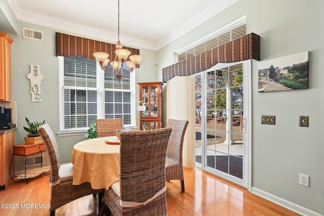 dining area with light wood finished floors, plenty of natural light, visible vents, and crown molding