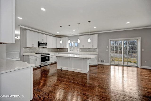 kitchen with dark wood-style flooring, light countertops, white cabinets, appliances with stainless steel finishes, and backsplash